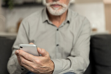 Man using smartphone at home for communication and online tasks in living room