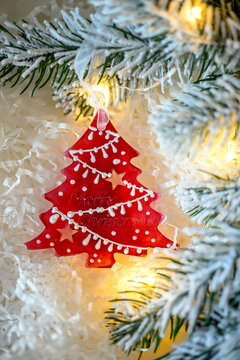 Handmade Christmas tree ornament made of epoxy resin hanging on a decorated Christmas tree. Festive holiday decoration with sparkling details, warm lights and soft bokeh in the background. 