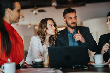 A group of colleagues gathers around a laptop, engaged in a focused discussion. Warm lighting, coffee cups, and a casual workspace convey collaboration, creativity, and productive brainstorming.