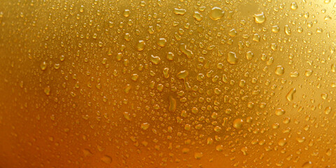 A golden abstract background with water droplets and dewdrops on the surface. It gives a fresh, moist, and cool impression with golden yellow tones.