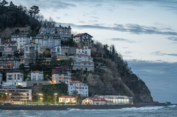 Luxury residential buildings on a cliff overlooking the sea at twilight.