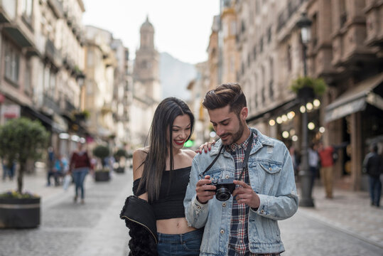 Young couple talking and walking in the city when review images on camera