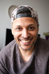 A man wearing a hat and a gray shirt is smiling