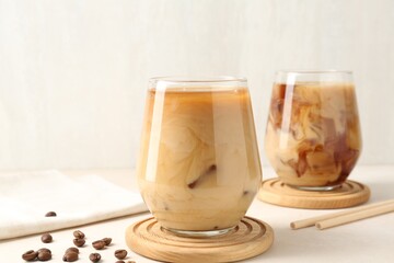 Tasty iced coffee with milk and beans on white table