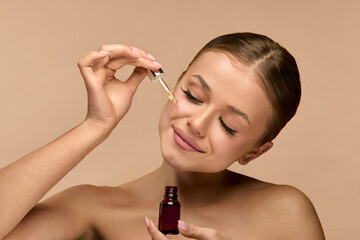 Happy woman, skincare and serum on face in studio for beauty, dermatology or collagen on brown...