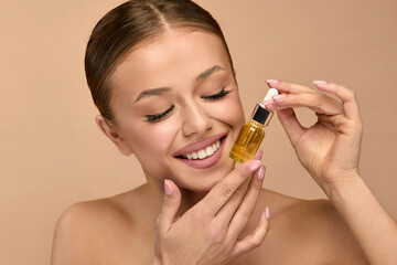 Beauty woman holds serum for skincare in studio, focusing on facial treatment for healthy skin in...
