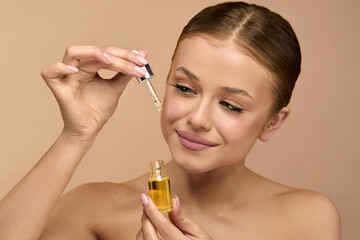 Beauty woman applying serum for skincare in studio with natural light to enhance skin glow and...