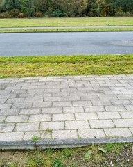 Obraz premium Paved sidewalk edges green grassy area along a road in a quiet rural setting during autumn season