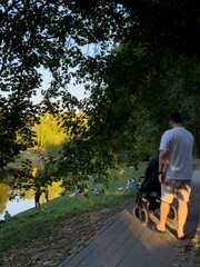 Man with Stroller by Pond in Park Sunset time