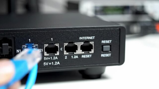 Closeup of hands connecting a blue ethernet cable to a network device
