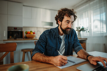 Man working remotely from home writing notes