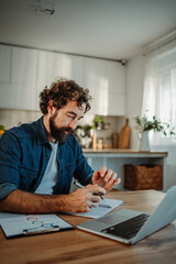Fototapeta premium Man writing notes working from home kitchen