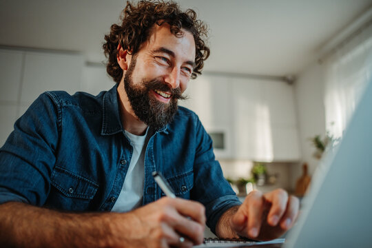 Bearded man freelancing from home making notes