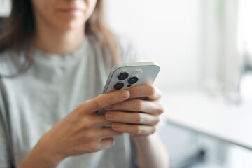 Woman holding smartphone and texting in bright room