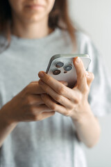 Woman holding smartphone and typing message indoors