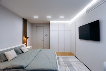 Apartment bedroom featuring soft green bedding and ambient lighting
