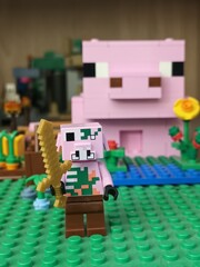 Fototapeta premium Minecraft Lego pig character holding a golden sword in a blocky landscape