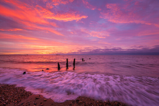 Crimson Display Colorful Purple and Pink Sunrise Over Ocean Waves