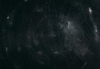 Abstract background of a scratched black surface with dust and circular patterns, suitable for backgrounds, textures, design elements, and overlays.