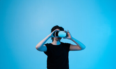 Woman adjusting virtual reality headset on blue background while preparing for immersive experience