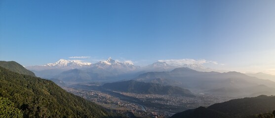 Panoramic view of snow-capped mountains and a valley below under a clear blue sky, Sarangkot, Pokhara, Nepal