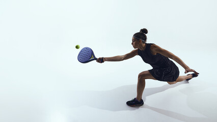 Woman lunges sideways hitting ball with padel racket in studio. Concept of UX storytelling, interface flow visuals, digital communication, and athletic movement analysis.