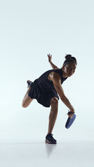 Padel player lunges low to return fast ball on white studio floor. Concept of padel defense, dynamic movement and commercial imagery for sportswear and equipment promotion.