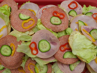 Sandwiches with sausage and cheese, garnished with cucumber and peppers &ndash; a popular savory snack for events and parties, perfect for any buffet.