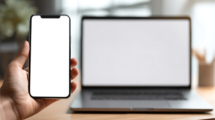 Hand holding smartphone with blank screen next to laptop image