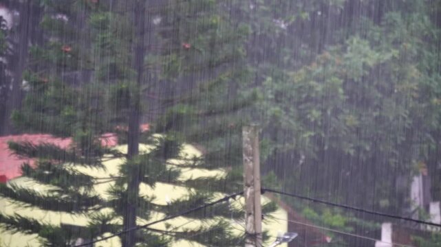 Heavy rainfall in a ecofriendly city with infrastructures and trees in the background.