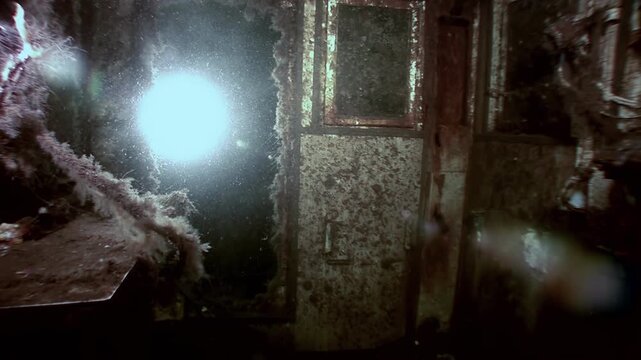 Explore the corroded cabin of a sunken ship on the floor of the White Sea. Algae grows around metal structures, illuminated by an underwater light source during the daytime dive.