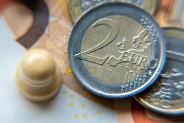 Coins and a game piece on a currency note showing details of money and leisure activities