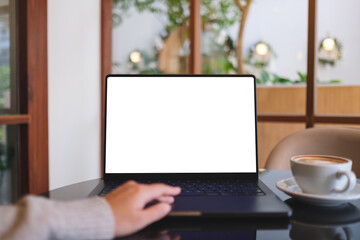 Mockup image of a woman working and typing on laptop computer with blank white desktop screen in...