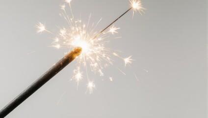 Sparkling Celebration - A Close-Up of a Lit Sparkler Against a Neutral Background.