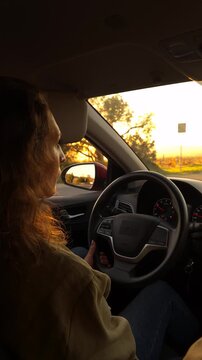 Driving sunset woman, traveling alone in a modern car on a highway road during golden hour light.