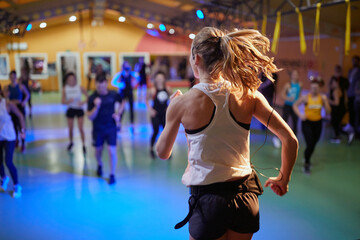 Active instructor jumping in front of class showing exercise workout. Healthy lifestyle, sport, workout concept