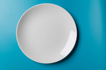 Flat lay of a white dinner dish on a blue background.