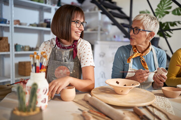 Smiling people having fun while painting pot on a pottery workshop. . Creative, hobby ,activities...