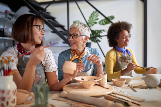 pottery making workshop . group of people painting pot with brushes. Creative, hobby ,activities concept - Powered by Adobe