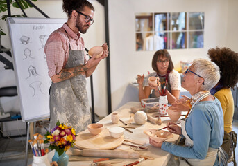 pottery making workshop . group of people painting pot with brushes. Creative, hobby ,activities concept