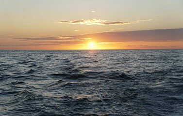 Naklejka premium Golden sunset over rippling ocean waves, with dramatic clouds reflecting warm light, capturing nature’s tranquil beauty at day’s end near St Petersburg, Florida, U.S