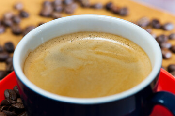 Frothy Coffee in Blue Cup on Red Saucer Close-Up