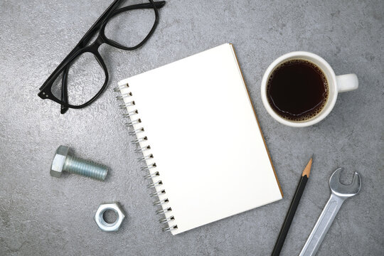 Notebook with glasses and wrench on stone texture background. Business desk office. Top view