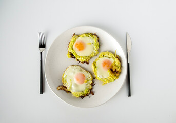 Three fried eggs with zucchini lie on a white plate, top view, space for text