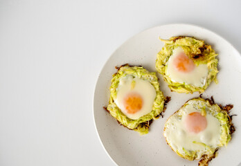 Fried eggs with zucchini on a white plate, top view, space for text