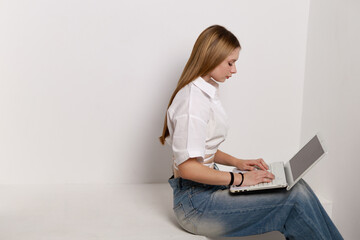 Cute Caucasian teenage girl sitting on the couch with a laptop	