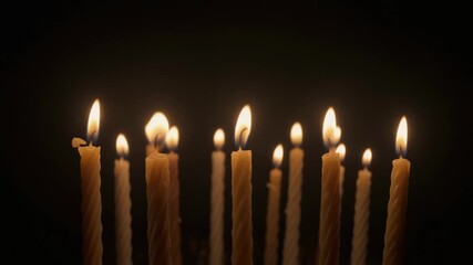 Many thin church candles burning with bright flames on a black background. Spiritual vigil, prayer, or memorial concept for religious holidays or remembrance events