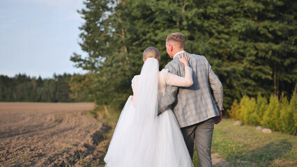 Newlyweds holding hands, walking through lush green landscape, sharing intimate moment after wedding ceremony