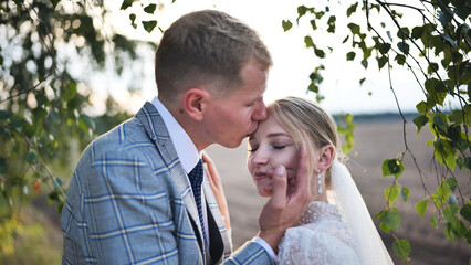 Newlyweds embracing beneath birch branches, showcasing intimate wedding day connection and heartfelt romantic emotion