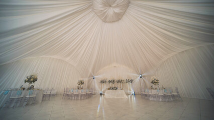 Elegant wedding table setup with floral arrangements under a white tent, ready for celebrating the special day